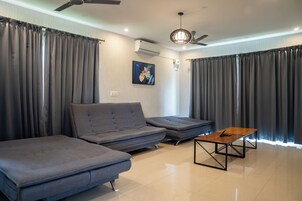 Una sala moderna con un sofá, un rincón de descanso más pequeño, una mesa de centro y un ventilador de techo.