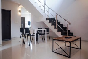 A modern interior with a staircase, a dining area, and a small table. - White Mist by NAVA (Devanahalli)