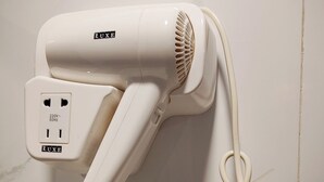 Een witte haardroger met een snoer aangesloten op een stopcontact.