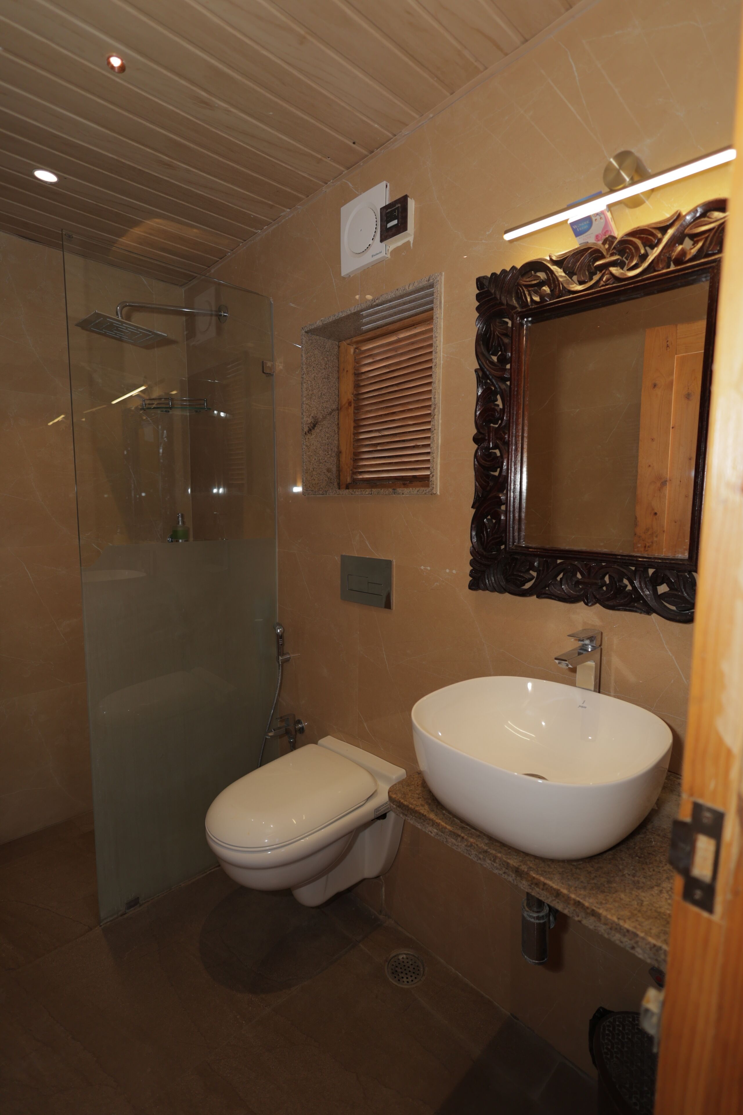 Een badkamer met een douchecabine van glas, een wit toilet en een groot wastafelmeubel met een houten blad.