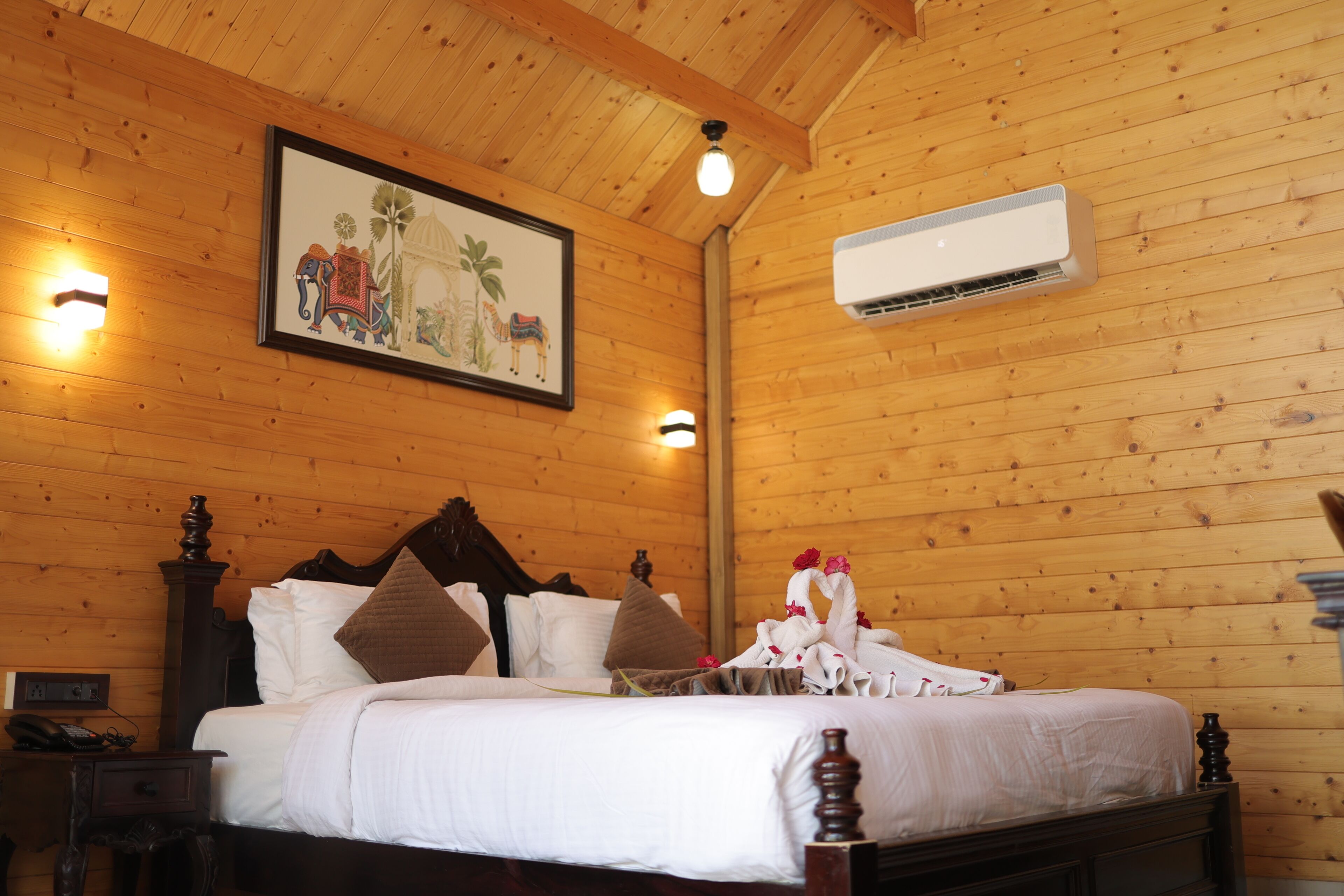 Habitación con paneles de madera, una cama, una mesita de noche, aire acondicionado montado en la pared y un cuadro enmarcado.