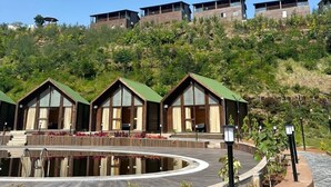 Un hilera de cabañas de madera con techos verdes, con un cerro de fondo.