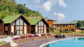 A resort with a swimming pool, wooden cabins with large windows, and a landscaped garden.
