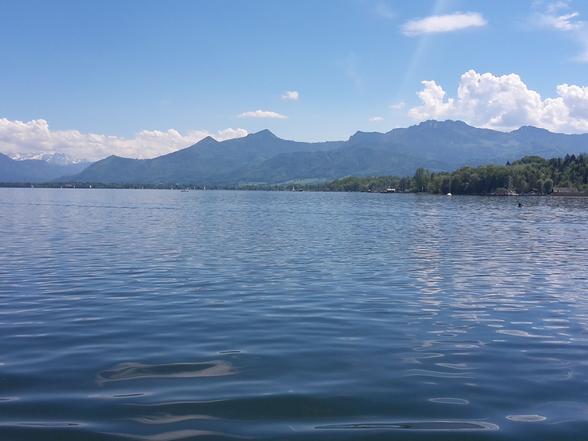 A calm lake with mountains in the background and a clear sky.