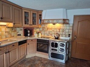 Una cocina con armarios de madera, cafetera, hervidor de agua y lavavajillas.
