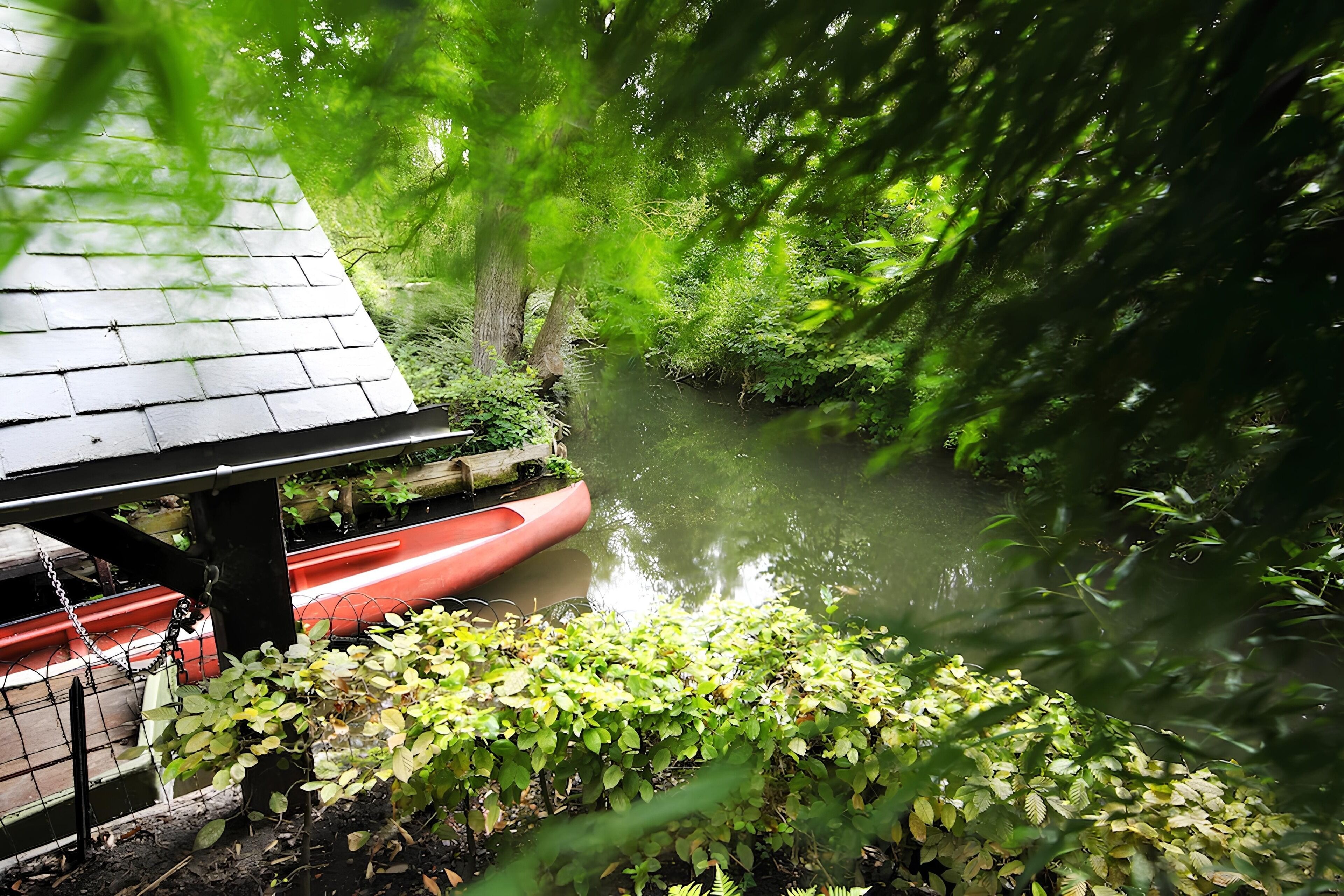 Un río con una canoa roja amarrada bajo una estructura de madera.
