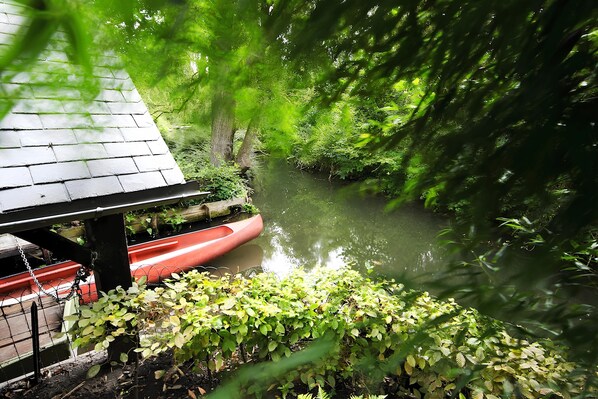 A river with a red canoe docked under a wooden structure.