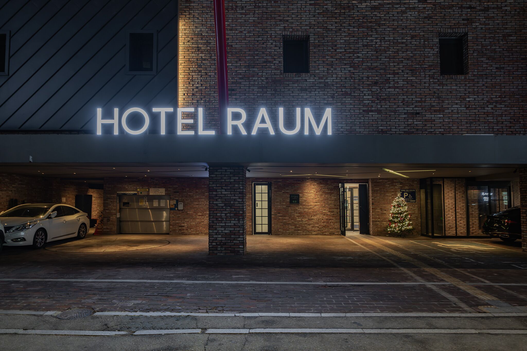 A hotel entrance with a sign reading "HOTEL RAUM" and a Christmas tree decoration.