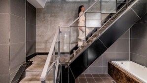A modern bathroom with a glass staircase, a bathtub, and a shower area. - Jamsil Raum Tourist Hotel (Seoul)