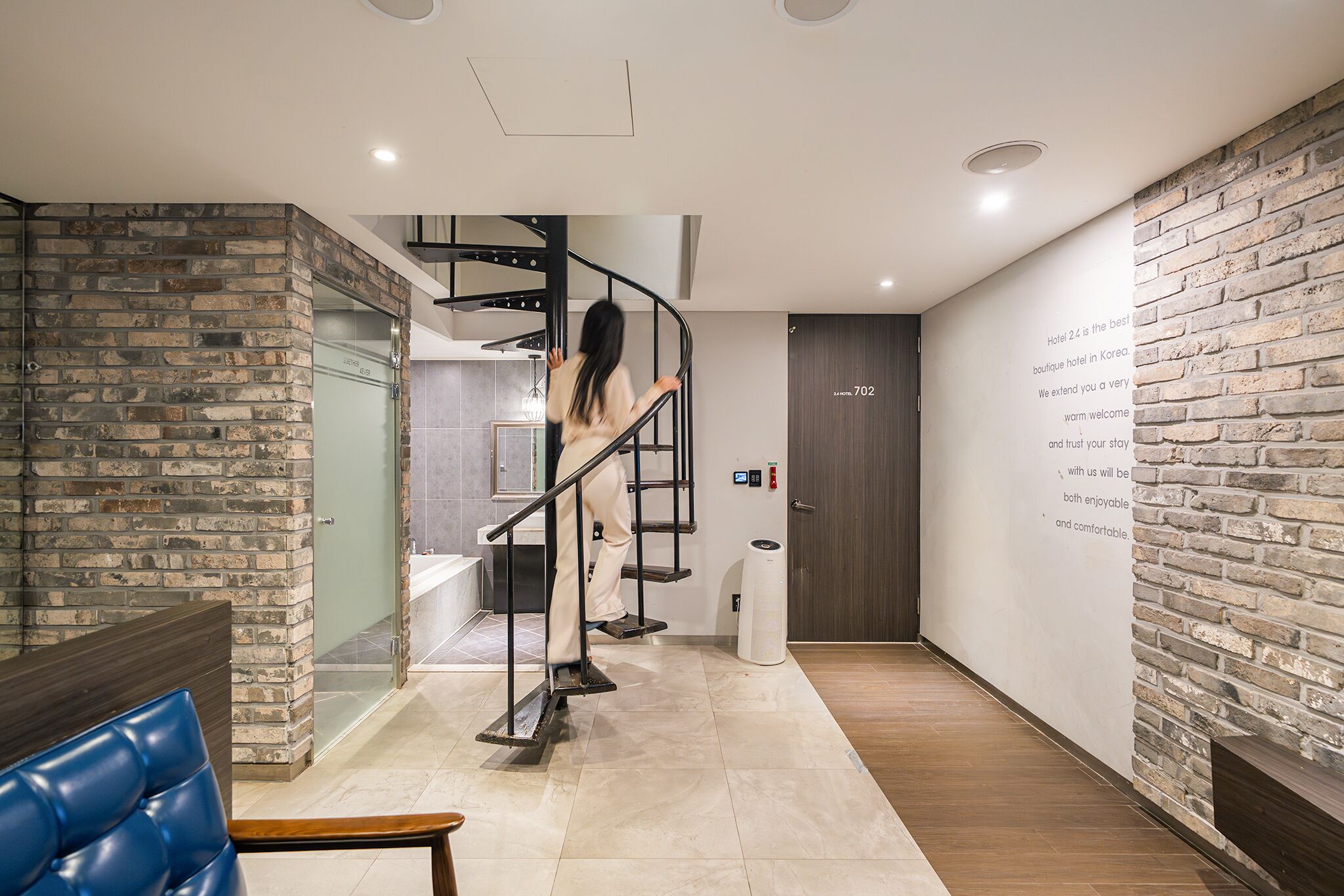 Un moderno vestíbulo de hotel con una pared de ladrillo, una escalera de caracol y un mostrador de recepción.