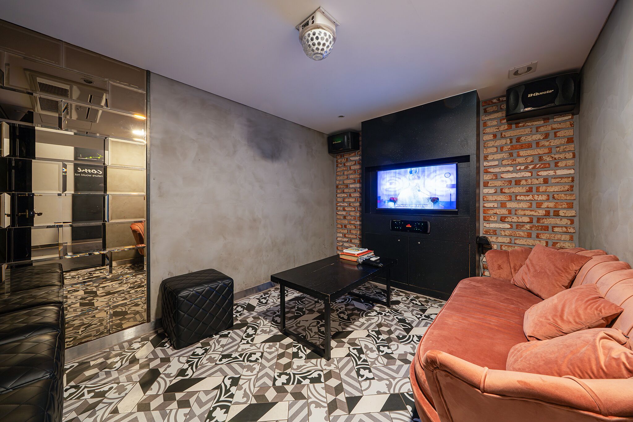 A modern living room with a sofa, a coffee table, and a TV mounted on a brick wall.