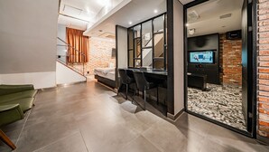 A modern hotel room with a desk, chairs, a television, and a brick wall. - Jamsil Raum Tourist Hotel (Seoul)