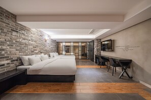 A modern hotel room with a brick wall, a large bed, a desk, and a fireplace. - Jamsil Raum Tourist Hotel (Seoul)