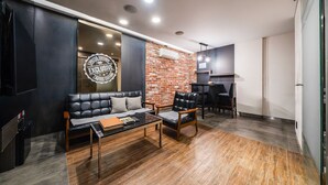 A modern living room with a leather sofa, a coffee table, and a brick accent wall. - Jamsil Raum Tourist Hotel (Seoul)