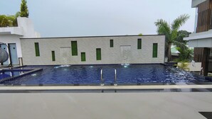 Una piscina con pared texturizada y detalles en ventanas verdes.
