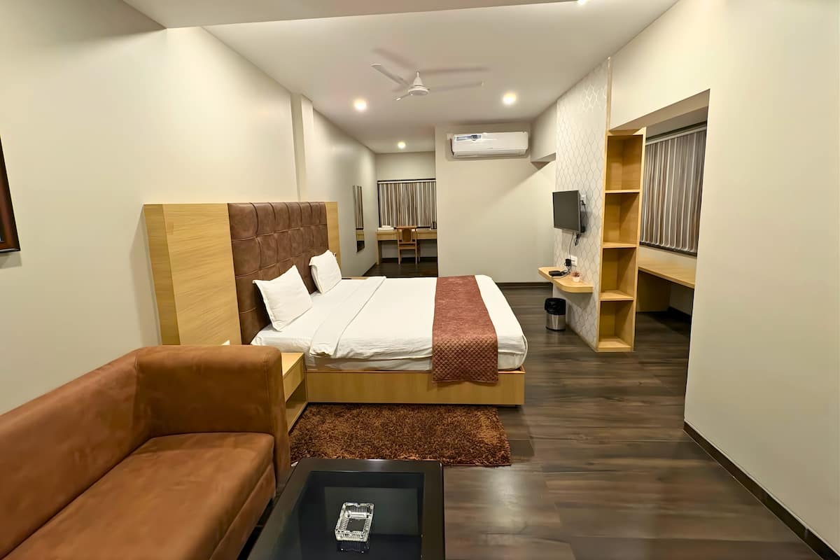 Een moderne hotelkamer met een groot bed, een bruine leren bank, een kleine tafel en een televisie.