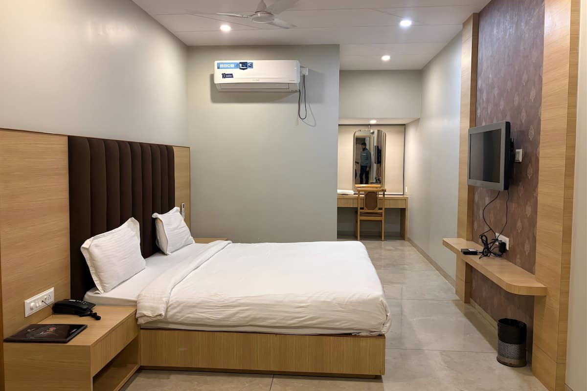 Een moderne hotelkamer met een bed, nachtkastje, telefoon en bureau met een stoel.