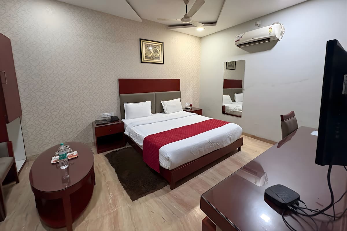 Een hotelkamer met een bed, nachtkastje, bureau en een flatscreen televisie.