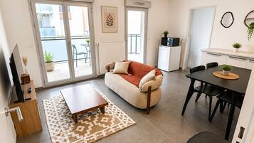 Una sala moderna con un sofá, una mesa de centro y un comedor con una mesa y sillas.