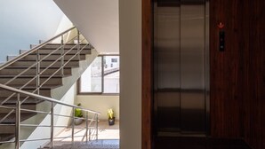 A modern interior with a staircase, a potted plant, and an elevator. - Hotel Aaradhya Crown (Devgad)