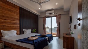 A modern hotel room with a large bed, two bedside tables, a desk, and a balcony with a view. - Hotel Aaradhya Crown (Devgad)