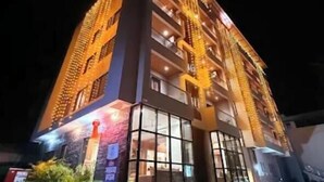 A multi-story hotel with illuminated exterior and large windows. - Hotel Aaradhya Crown (Devgad)