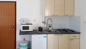 Ett kompakt kök med mikrovågsugn, vattenkokare, diskho och ett litet kylskåp.