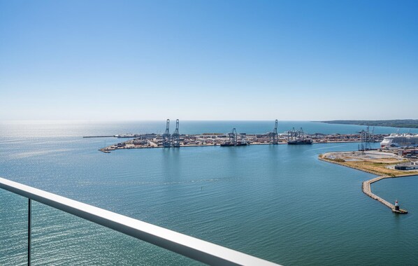 Un port costaner amb grues industrials i vaixells, vist des d'un punt elevat.