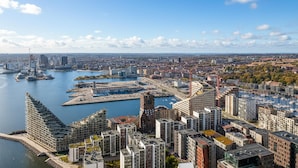 Un hôtel de grande hauteur au design moderne, situé près d’un front de mer avec un port de plaisance.