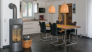Una cucina moderna con mobili bianchi, piano cottura integrato e zona pranzo con tavolo in legno e sedie nere.