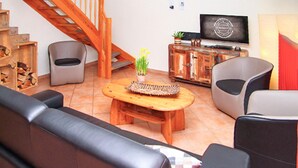 A living room with a wooden coffee table, two sofas, a TV, and a staircase. - Cozy home in Röbel with lake view (Röbel)
