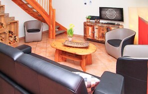 A living room with a wooden coffee table, two sofas, a TV, and a staircase. - Cozy home in Röbel with lake view (Röbel)