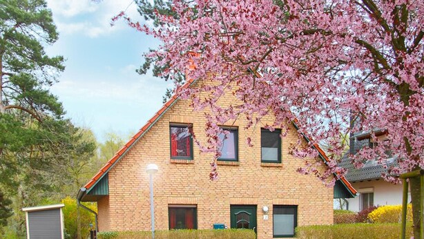 A two-story brick house with a sloped roof, multiple windows, and a small attached garage. - Cozy home in Röbel with lake view (Röbel)