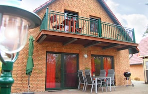 A two-story house with a balcony, a patio with chairs and a table, and a barbecue grill. - Cozy home in Röbel with lake view (Röbel)