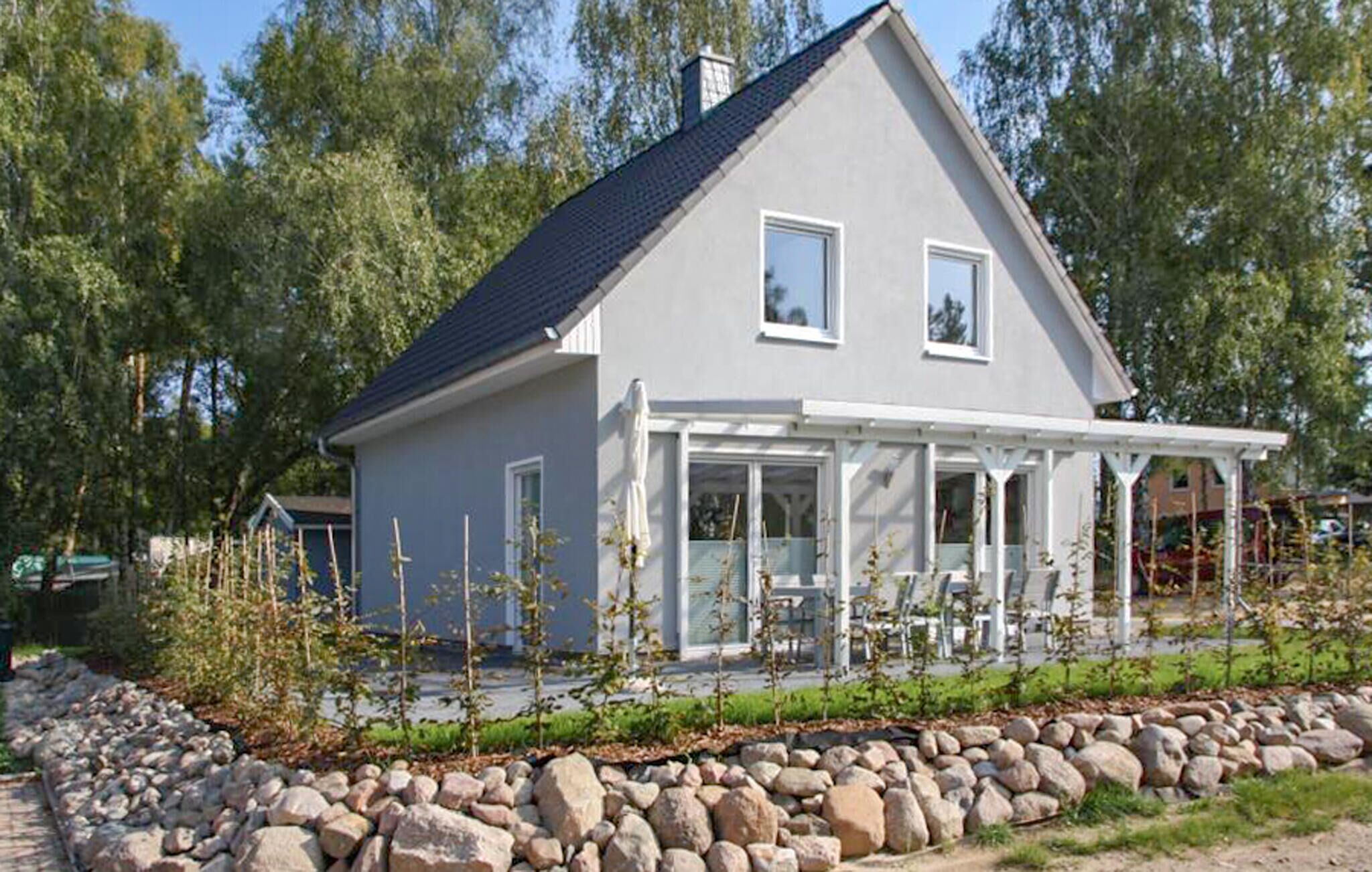 Kaksikerroksinen talo, jonka ulkoseinät ovat harmaat, katto tumma ja jossa on katettu kuisti.