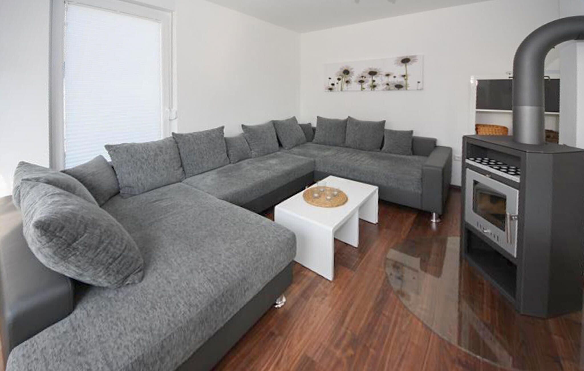 Un saló modern amb un sofà modular gris, una taula de centre blanca i un foc de llenya.