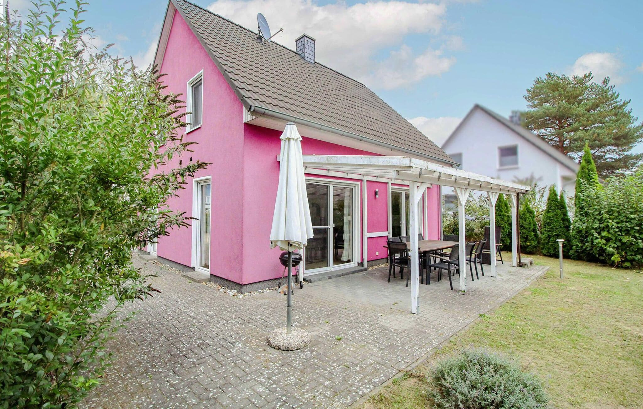 A pink house with a covered patio, a satellite dish, and a garden.