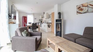 A modern living room with a sofa, armchair, and coffee table. A kitchen with white cabinets and a stove is visible in the background. - Pet friendly home in Röbel with WiFi (Röbel)