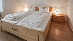 A neatly made bed with white linens and pillows, a wooden headboard, and bedside tables with lamps. - Pet friendly home in Röbel with WiFi (Röbel)
