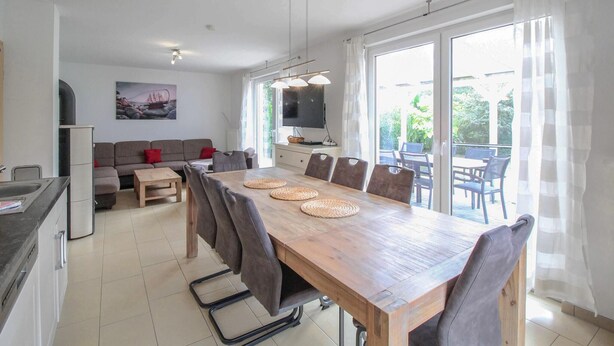 A modern living room with a sofa, a dining table with chairs, a TV, and a kitchen area with a sink and cabinets. - Pet friendly home in Röbel with WiFi (Röbel)