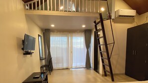 A spacious bedroom with a loft area, a television, a desk, and a wardrobe. - BLOOMS AND BERRIES AGRO TOURISM (Kalamgaon kalamkar)