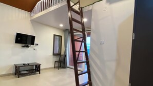 A room with a lofted sleeping area, a television, a desk, and a chair. - BLOOMS AND BERRIES AGRO TOURISM (Kalamgaon kalamkar)