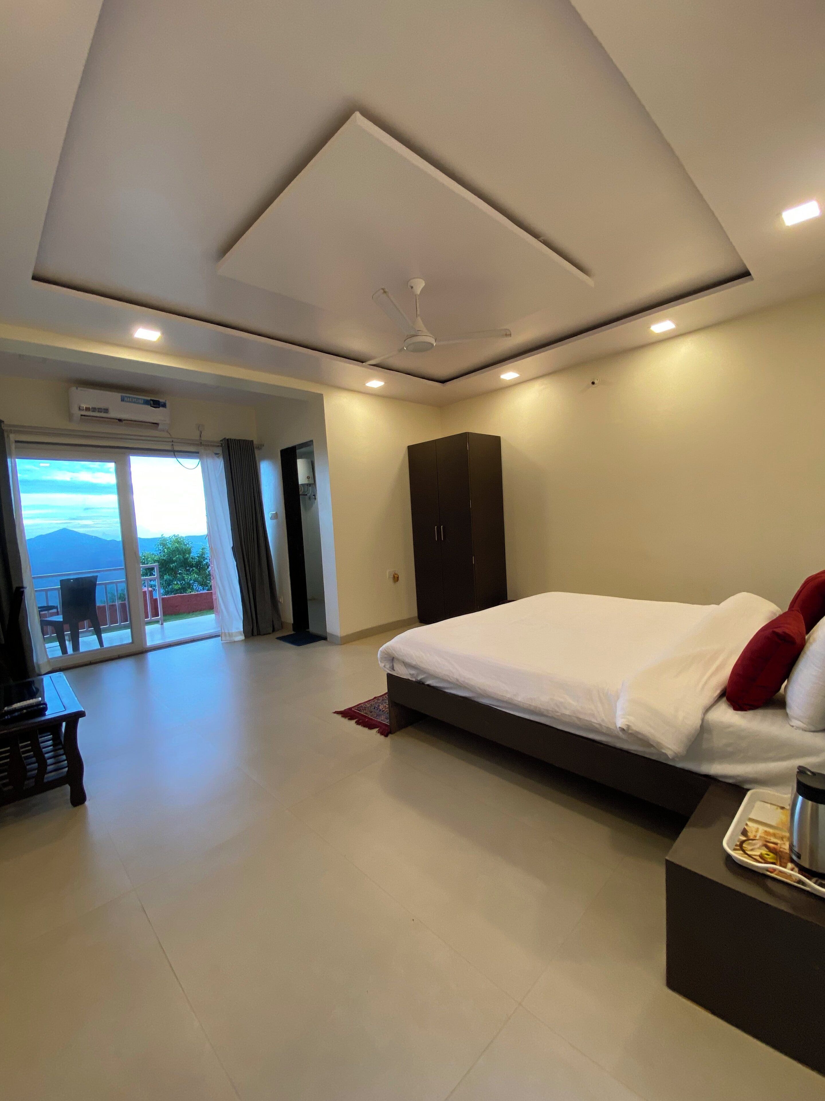 A modern bedroom with a large bed, a wardrobe, and a television on a desk.
