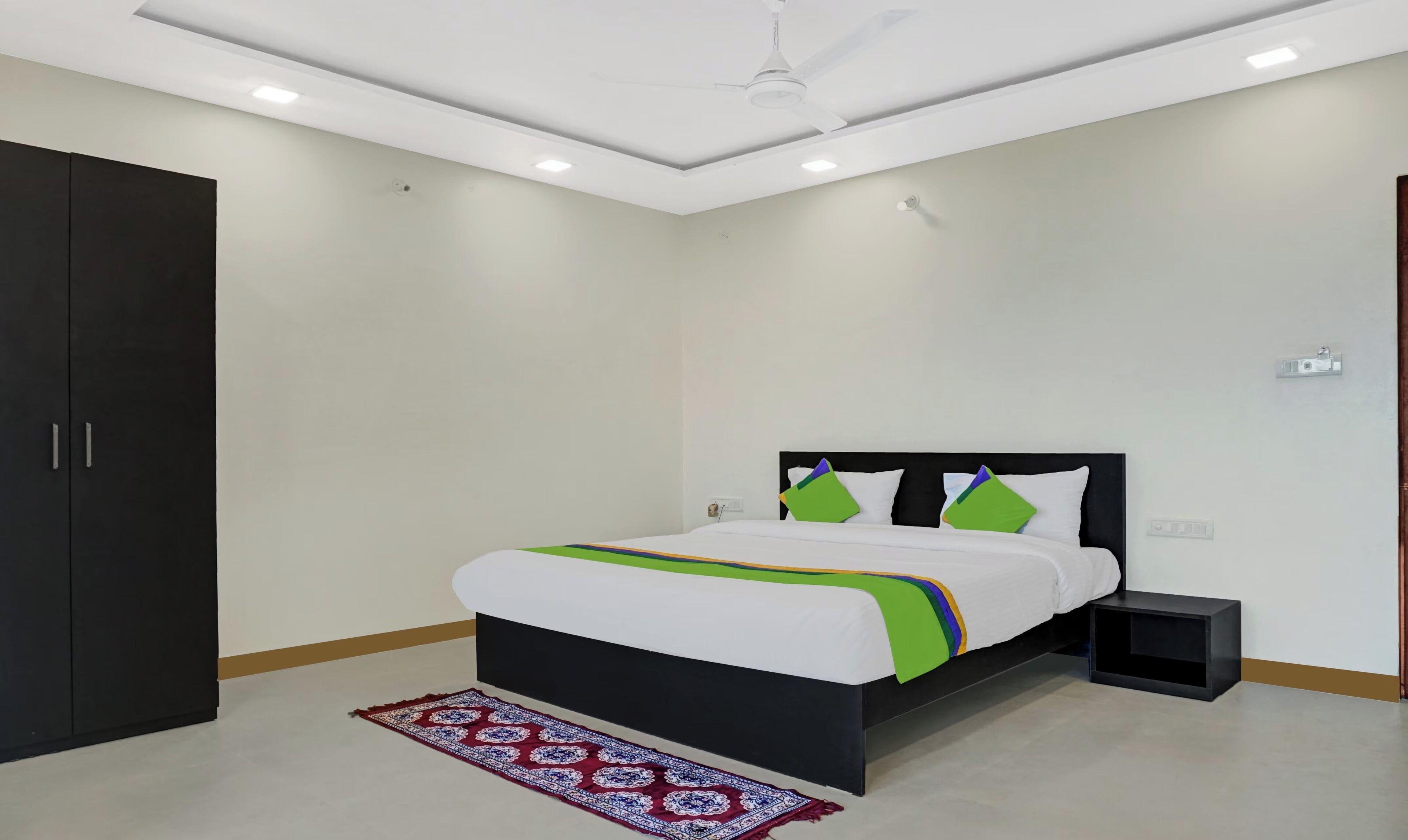 A bedroom with a bed, a wardrobe, a bedside table, and a ceiling fan.