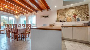 A modern kitchen with a stone backsplash, wooden cabinets, and a central island. - Stunning home in Chenac-Saint-Seurin-d' (Chenac-Saint-Seurin-d')