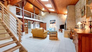 A spacious living area with a wooden staircase, a sofa, a TV, and a stone wall. - Stunning home in Chenac-Saint-Seurin-d' (Chenac-Saint-Seurin-d')