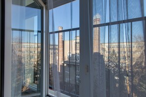 A window with a view of a building with multiple chimneys and a clear sky. - Superb Studio near Charles Square, Old Town (Prague)