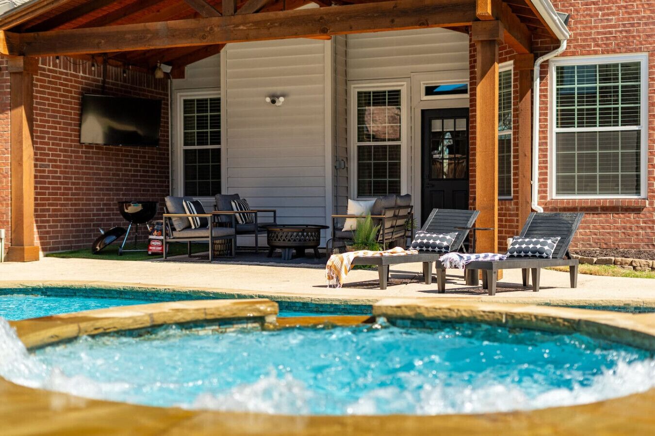 A pool area with lounge chairs and a barbecue grill.