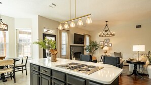 A spacious kitchen with a large island, dark cabinetry, and modern pendant lighting. - Designer-Styled Modern Farmhouse w/ Heated Pool (Allen)