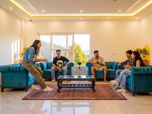Un salón moderno con un sofá azul turquesa, una mesa de centro y un ventanal con vistas a zonas verdes.